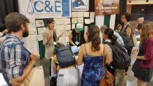 Lots of people congregate around a display table at a conference