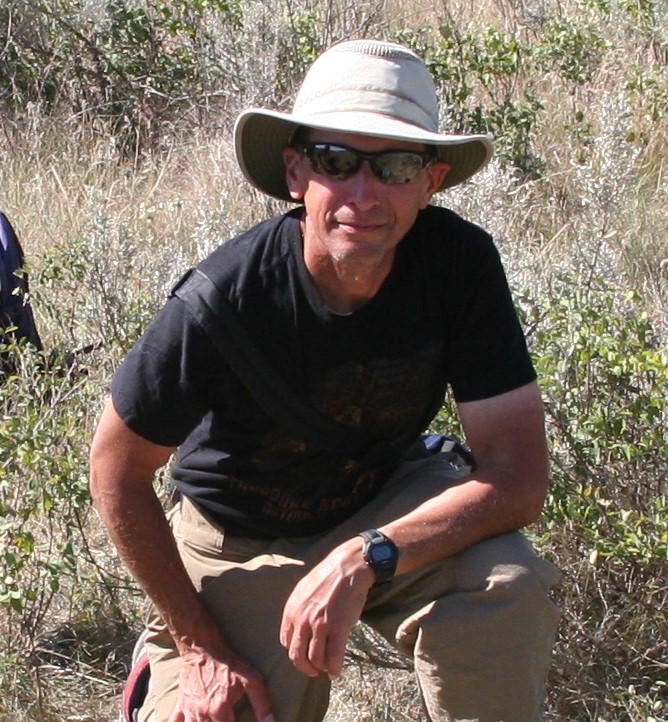 Man in hat and sunglasses smiles at camera