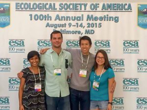 Group of four students standing in front of an Ecological Society of America 100th Annual Meeting banner