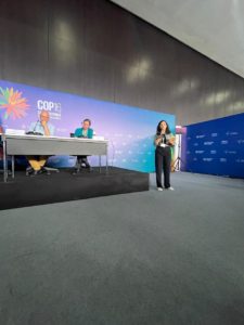 Woman standing speaking at a conference.