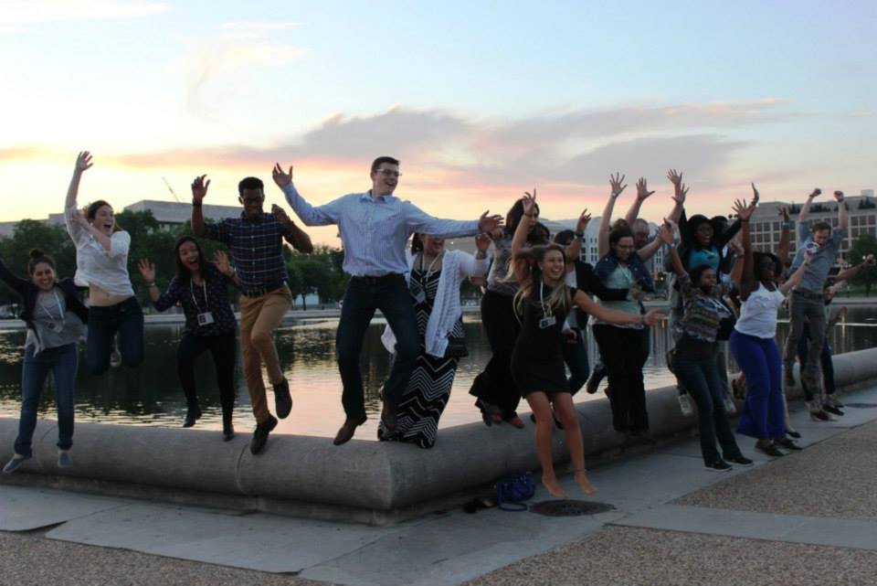 A group of students jump at synchronized time with their legs tucked beneath them.