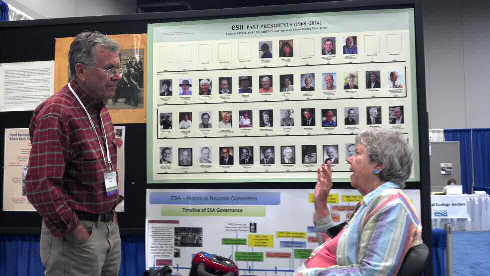 Jean Langenheim stands by a poster at an ESA annual meeting and discusses it with someone. 