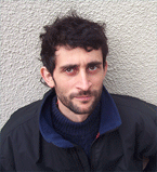 Portrait of Pedro Flombaum with a stucco backdrop.