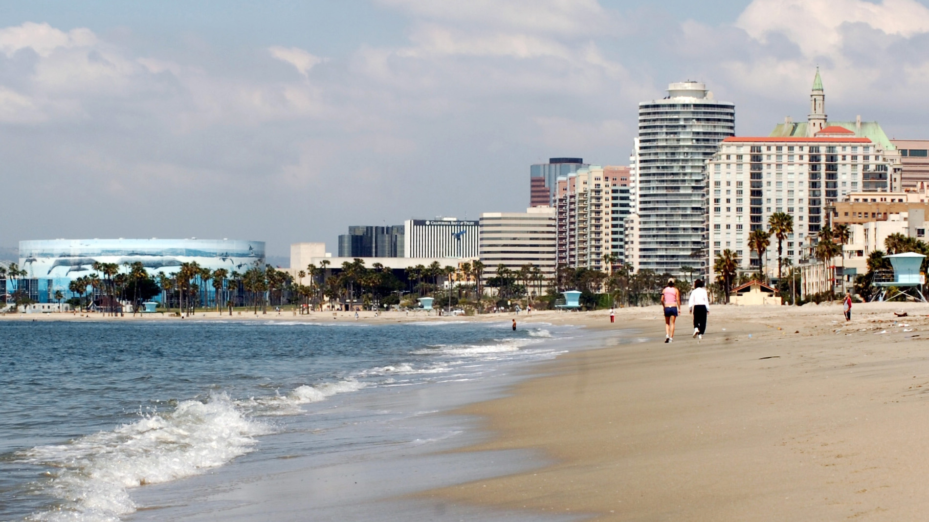 Two people walk along the beach.