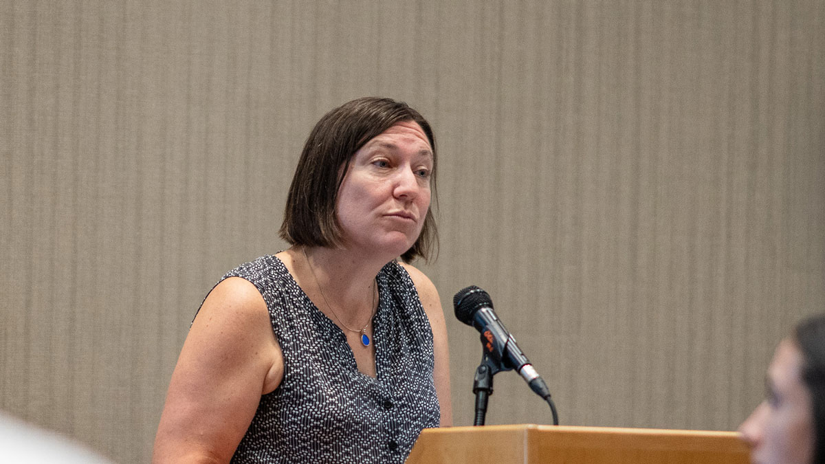 A presenter emphasizes a point as she stands at a podium. [Duplicate image]