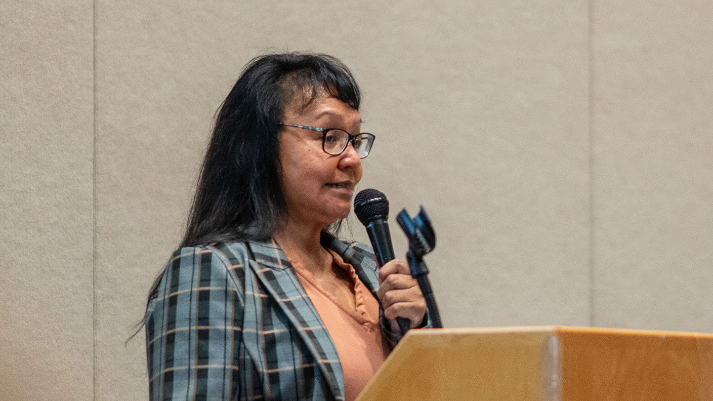 A speaker presents in front of her audience at a podium.