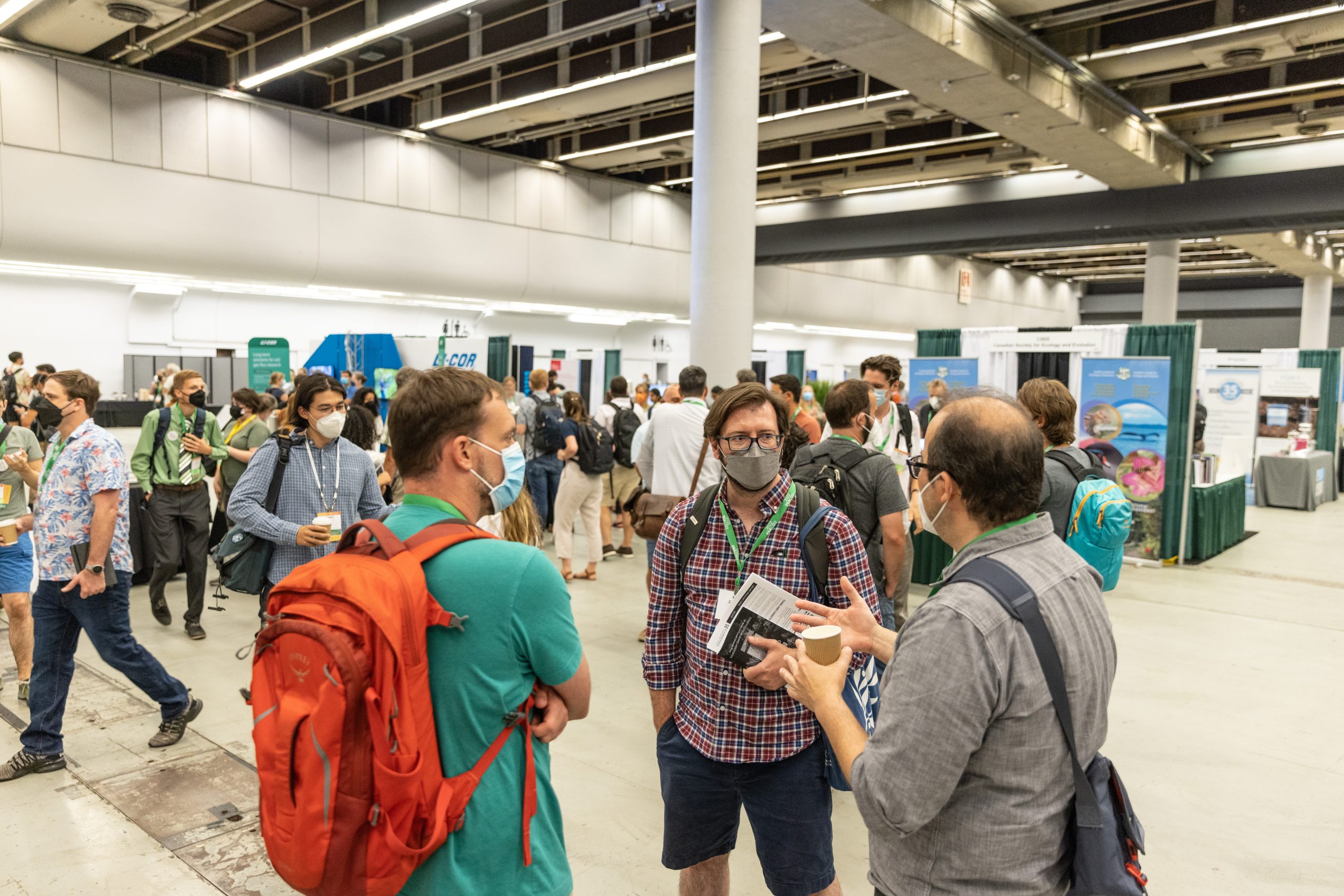 A group of attendees converse in a semi-circle in the meeting exhibit hall.