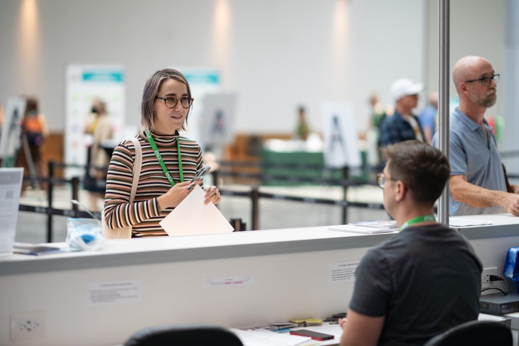 An attendee speaks with a volunteer at the help desk. 