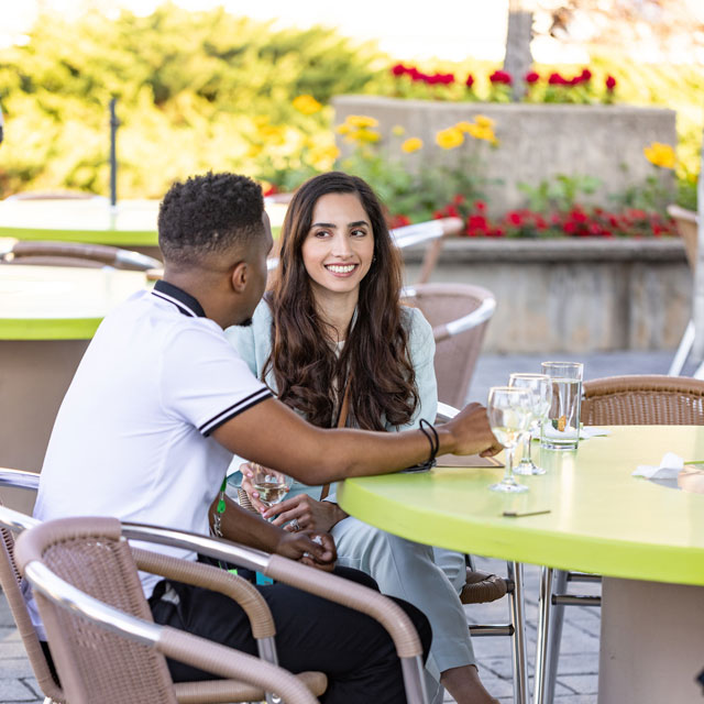 Two attendees enjoy a beverage seated at a table. 