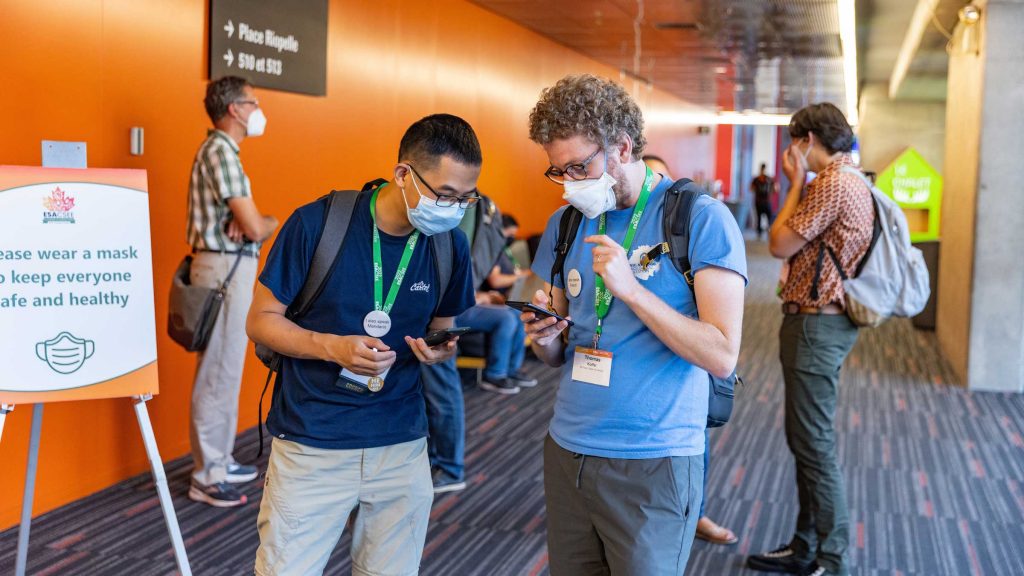 Two attendees explore the meeting schedule on their device.